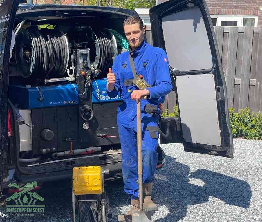 Een monteur bij de werkbus met grote hogedruk-slanghaspels, apparatuur voor hardnekkige afvoerverstoppingen in Soest