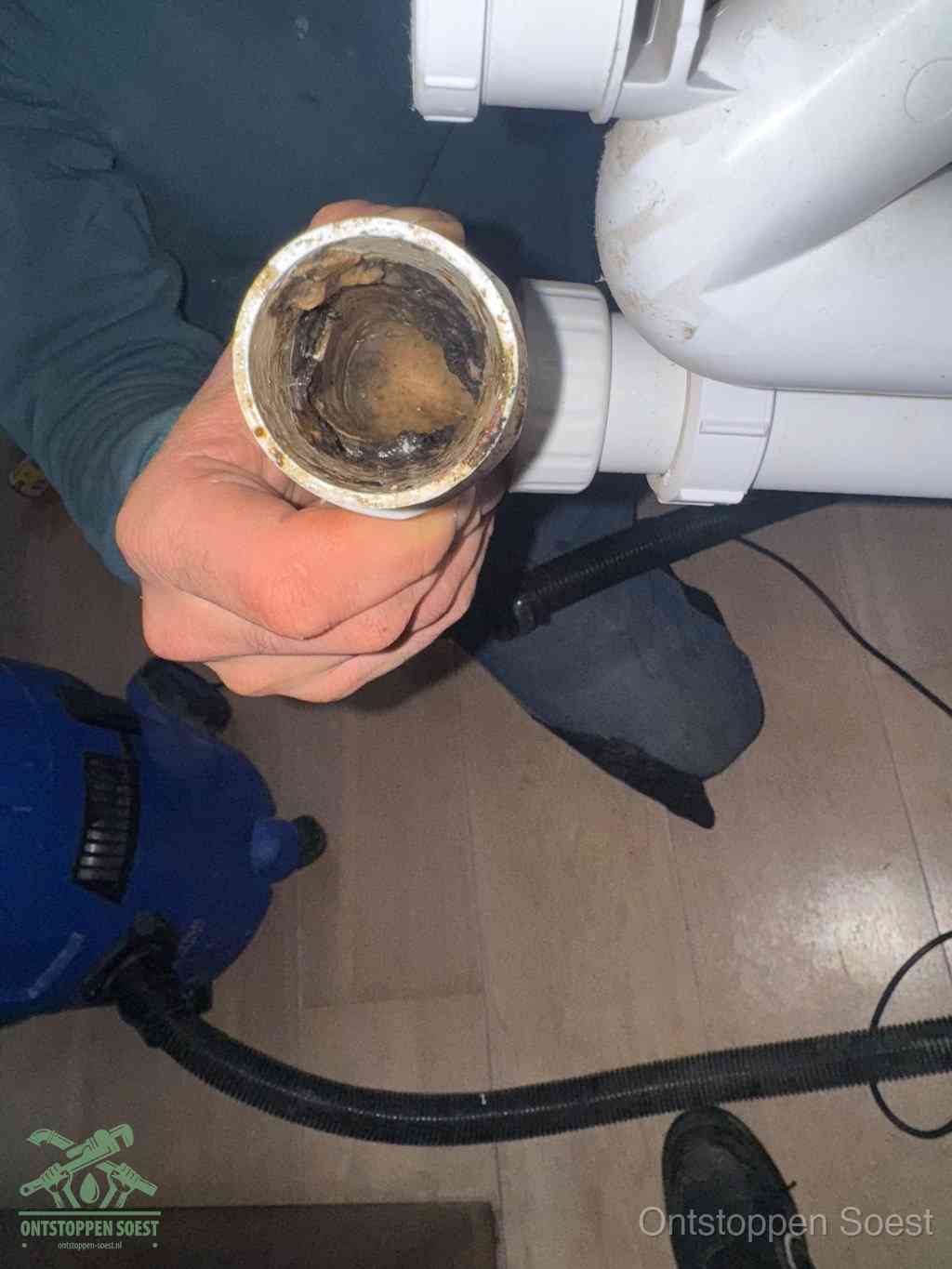 Een losgekoppelde afvoerbuis die van binnen volledig is dichtgeslibd met vet en aanslag, de meest voorkomende oorzaak van een verstopte gootsteen in Soest