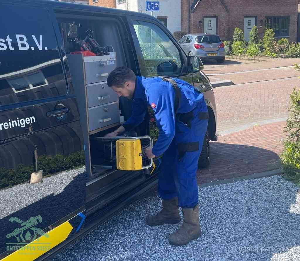 Een monteur pakt buiten op de oprit gereedschap uit de bedrijfsbus, het moment om een professional in te schakelen voor een verstopte afvoer in Soest