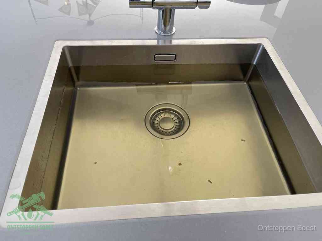 Stilstaand water in een rvs spoelbak dat niet wegloopt, een duidelijk signaal van een gootsteenverstopping in Soest
