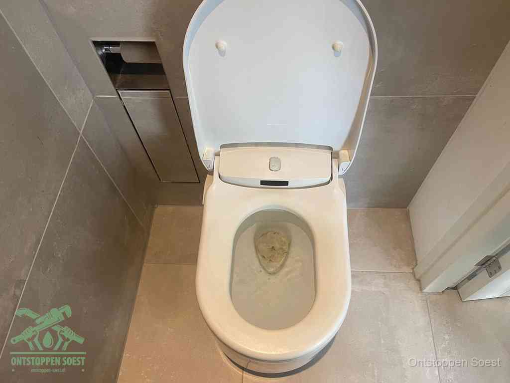 Een wit hangtoilet waarin een prop wc-papier op het water blijft drijven, een duidelijk signaal van een verstopte wc in Soest