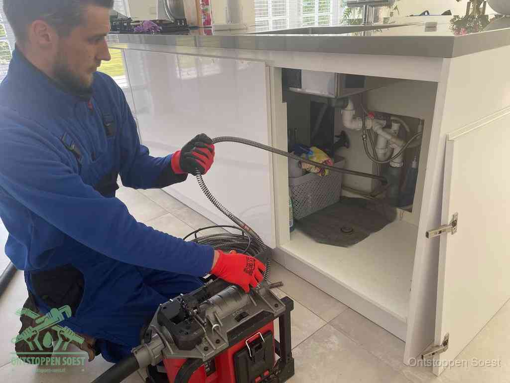 Een monteur reinigt de keukenafvoer grondig met een veermachine om terugkerende gootsteenverstoppingen te voorkomen in Soest