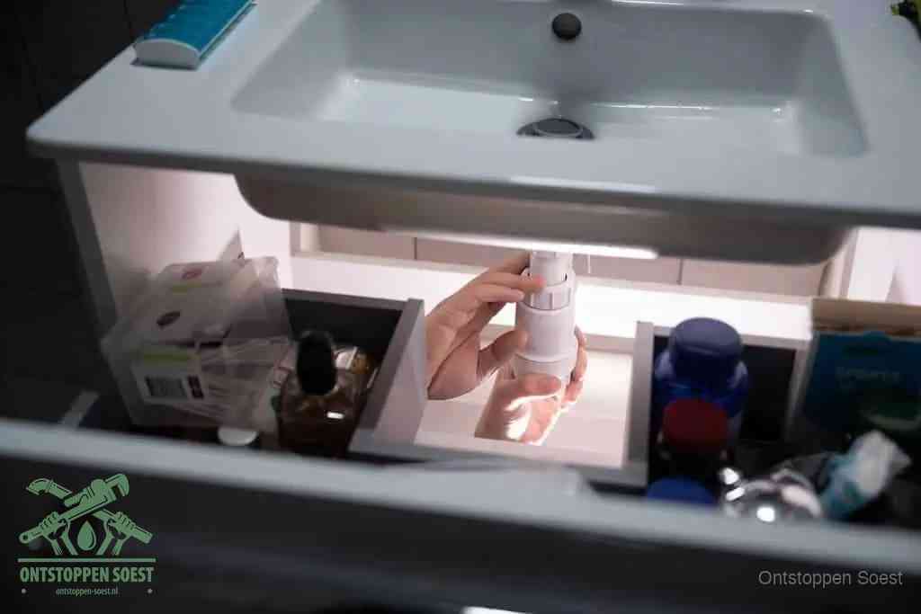 Een pompfles met zeep boven een wastafel in de toiletruimte, de warm water en afwasmiddel-methode om de wc te ontstoppen in Soest