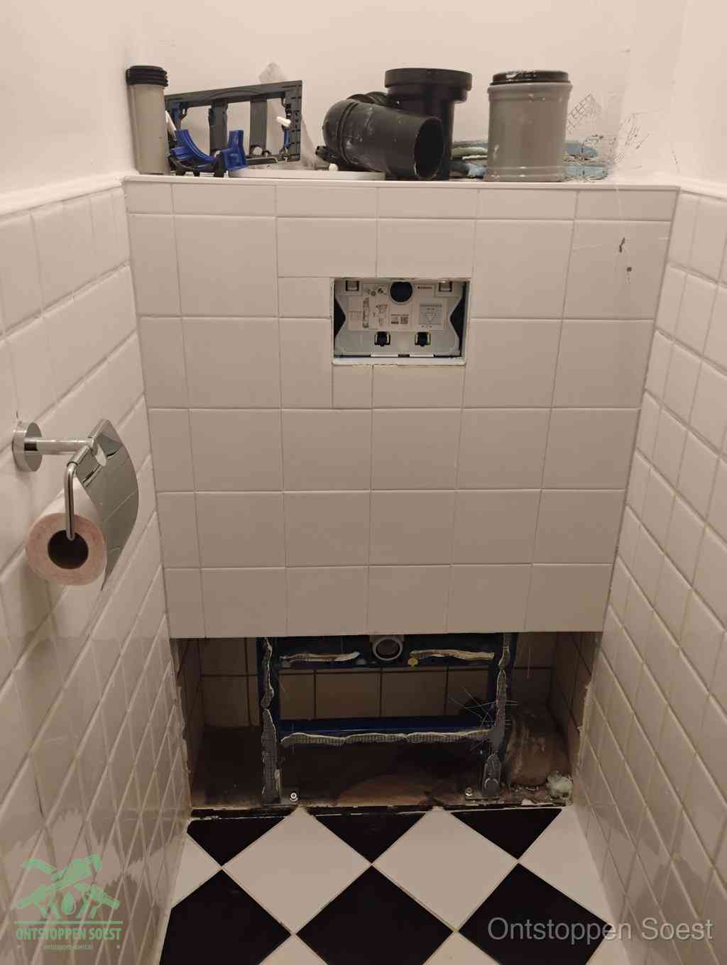 Een toiletruimte waar het hangtoilet en de inbouwreservoir-onderdelen zijn vrijgelegd voor onderhoud, periodiek nazicht voorkomt een wc-verstopping in Soest